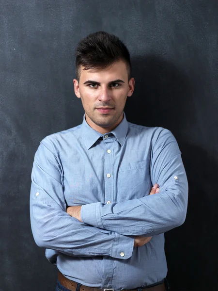 Portrait of a serious young man standing against chalkboard — Stock Photo, Image