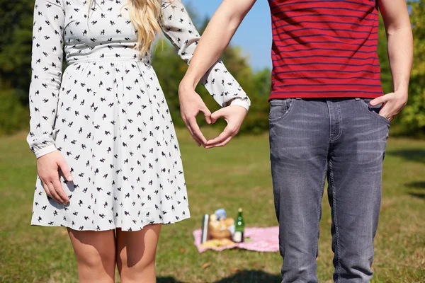 Hermosa pareja joven creando corazón con las manos, picnic, corazón — Foto de Stock