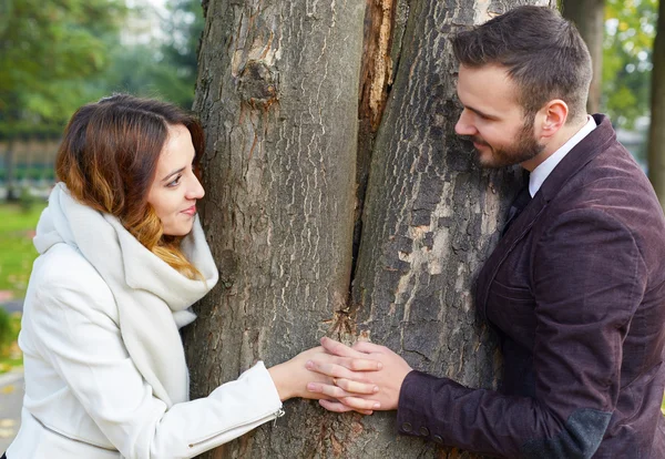 Пара шукає навколо протилежних сторін дерева — стокове фото