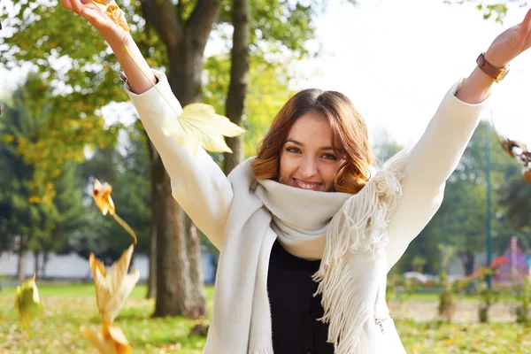 Portrait of cheerful young woman with autumn leafs in front of f — Stock Photo, Image