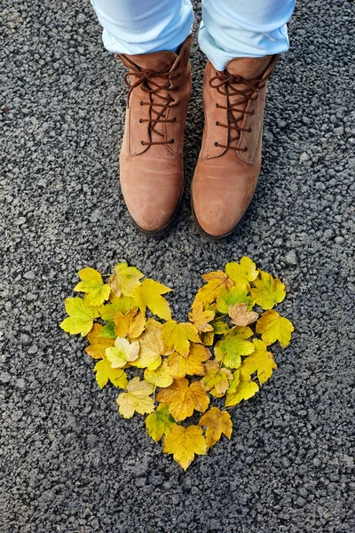 Kleurrijke hart gemaakt van de herfst bladeren, vrouw schoenen op asfalt, co — Stockfoto