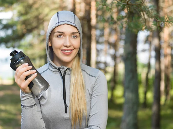 Mooie vrouw drinkwater op een zonnige dag in de natuur na jo — Stockfoto