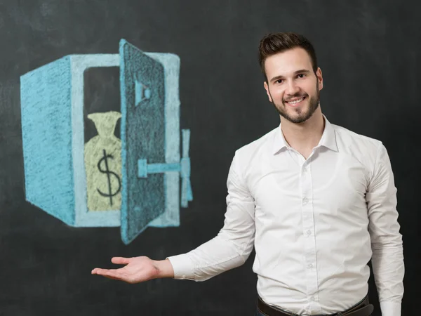 Joven con barba delante de la caja fuerte sonriendo y mostrando dinero — Foto de Stock