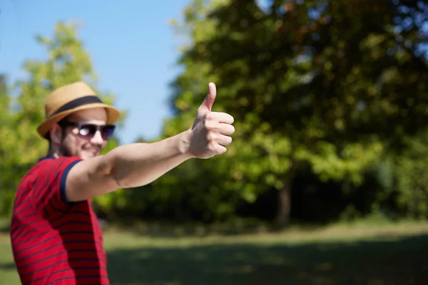 Casual jongeman zat naast de basis van een boom en weergegeven: — Stockfoto