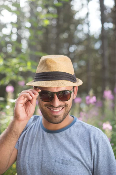 Bonito hipster sorrindo para a câmera em um dia ensolarado — Fotografia de Stock
