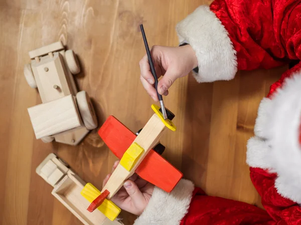 Santa Claus making toys. Painting and coloring wooden toy — Stock Photo, Image