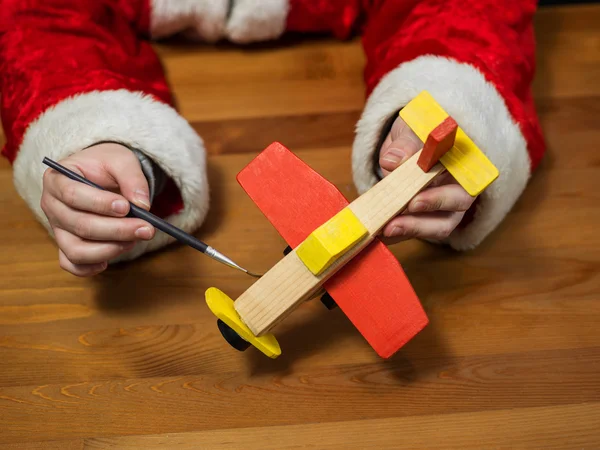 O Pai Natal a fazer brinquedos. Pintura e colorir brinquedo de madeira — Fotografia de Stock