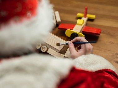 Noel Baba bir oyuncak uçak boyama atölyesinde oturmuş. Yatay kompozisyon.