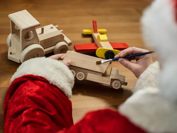 Santa Claus siedzi w swoim warsztacie malowanie samolotu zabawka. Hor — Zdjęcie stockowe