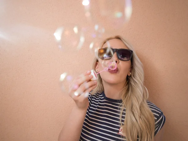 Glad ung kvinna som bär solglasögon med såpbubblor — Stockfoto