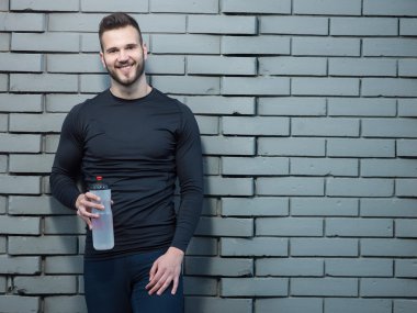 Tuğla duvar backg karşı duran genç atletik erkek portresi