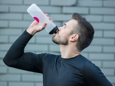 Tuğla duvar backg karşı duran genç atletik erkek portresi