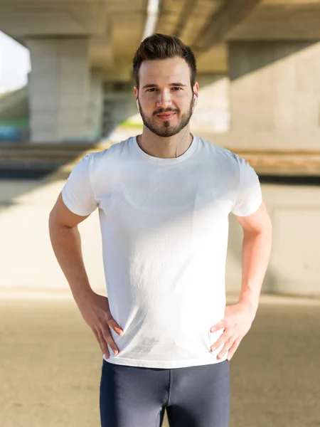 Joven hombre guapo corriendo a lo largo del terraplén cerca del río u — Foto de Stock