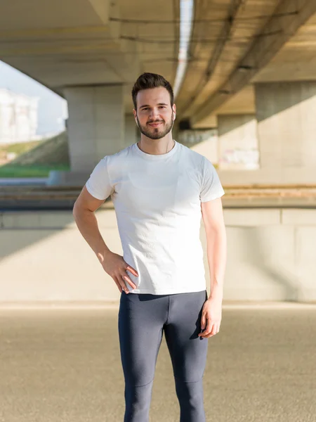 Joven hombre guapo corriendo a lo largo del terraplén cerca del río u — Foto de Stock