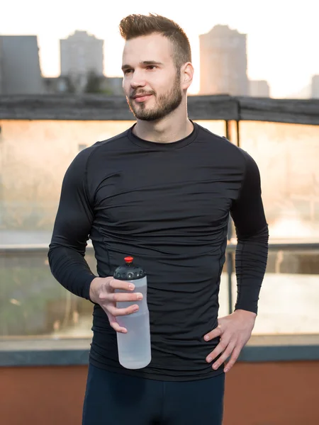 Atlético guapo hombre en negro entrenamiento ropa corriendo en el r — Foto de Stock