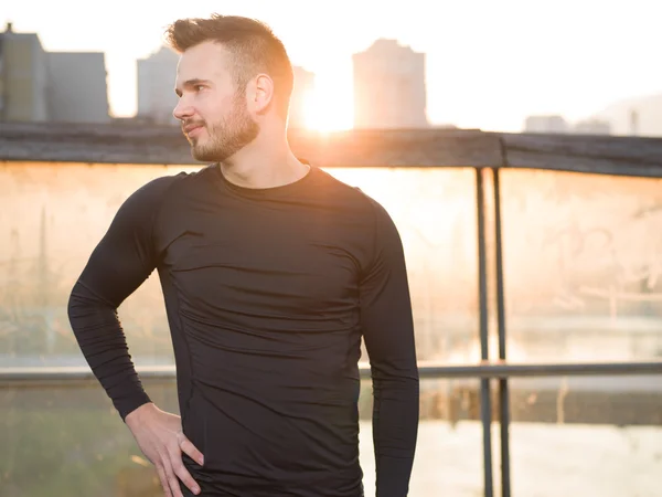 Atlético guapo hombre en negro entrenamiento ropa corriendo en el r — Foto de Stock