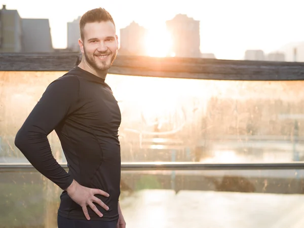 Atlético guapo hombre en negro entrenamiento ropa corriendo en el r — Foto de Stock