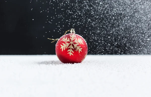 Christmas ball on snow, falling snow