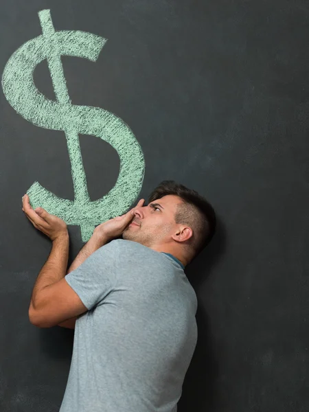 Lycklig man står framför dollartecken skrivit på en chalkbo — Stockfoto