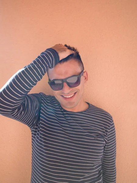 Ritratto di hipster felice che indossa occhiali da sole contro la schiena di colore — Foto Stock