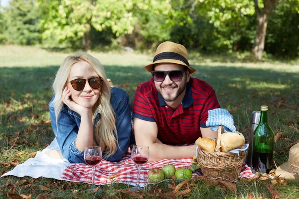 Happy young couple relaxing on the lawn in a summer park. Love c — Stock Photo, Image