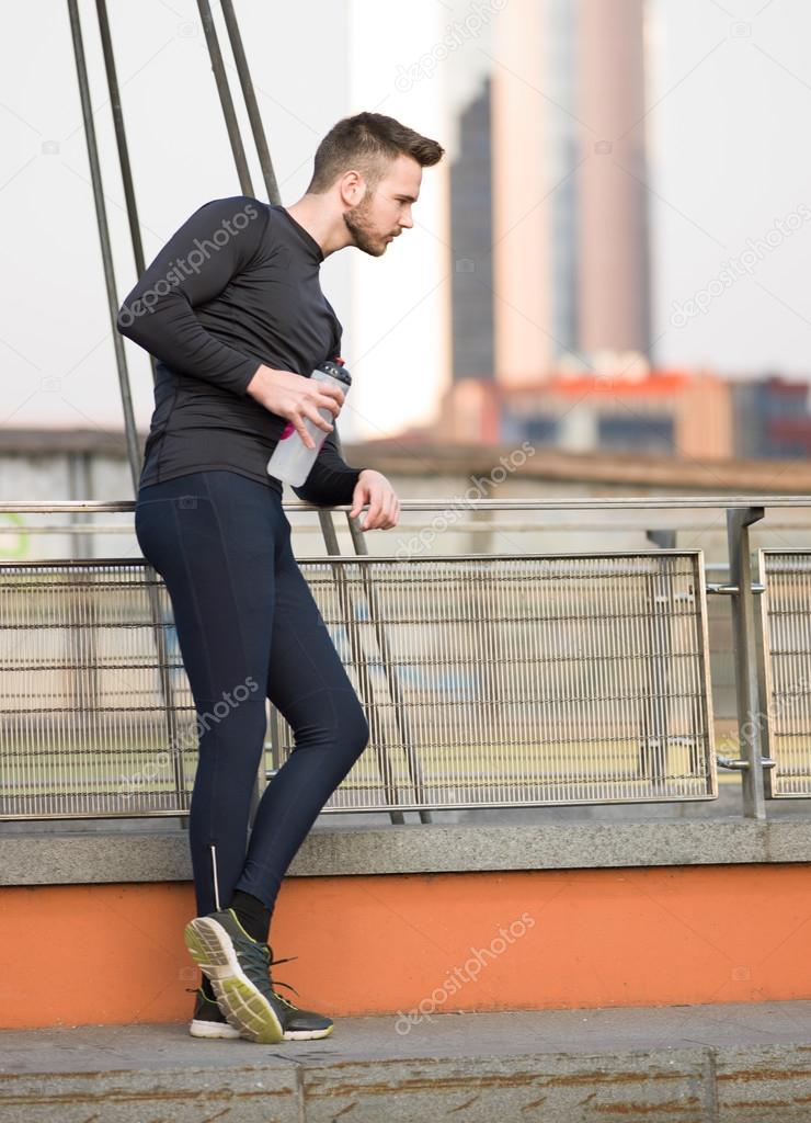 Young handsome man running along the embankment near the river u
