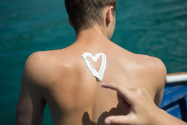 Man With Suntan Lotion At The Beach In Form Of The love simbols