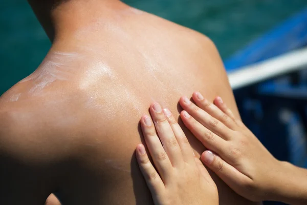 Hombre con loción bronceadora en la playa en forma de símbolos de amor — Foto de Stock