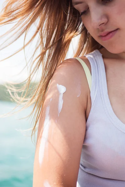 Beautiful woman applying suntan lotion during summer travel vacation