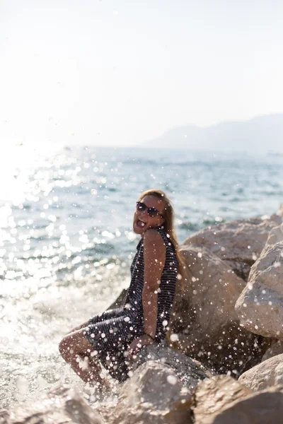 Vacker kvinna sitter på en sten och plaskade i havet — Stockfoto