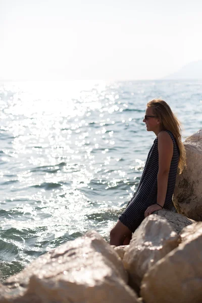 Vacker kvinna sitter på en sten och plaskade i havet — Stockfoto