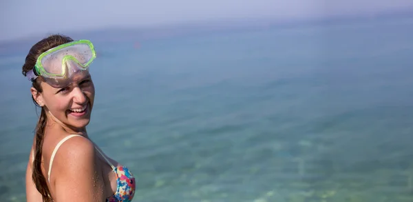 Mujer joven de pie en un mar y sosteniendo una máscara y snorkel —  Fotos de Stock