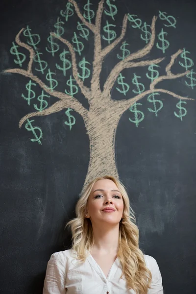 Mujer de negocios rubia feliz delante de tiza árbol de dinero dibujo — Foto de Stock