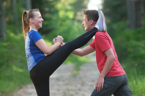Hombre y mujer haciendo ejercicios de estiramiento en el parque de verano. Jóvenes c —  Fotos de Stock