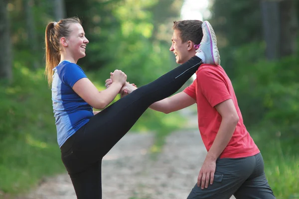 Мужчина и женщина делают упражнения на растяжку в летнем парке. Молодые c — стоковое фото