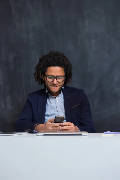 Portrait of happy smart black businessman sitting at desk in off — Stock Photo, Image