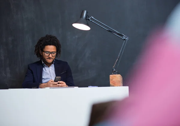 Retrato de feliz homem de negócios negro inteligente sentado na mesa em off — Fotografia de Stock