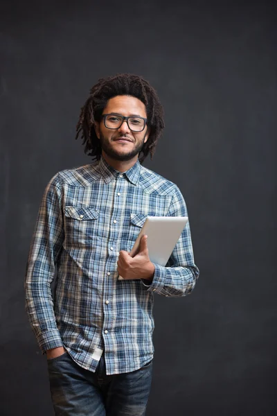 Enjoying his digital tablet. Cheerful young African man holding