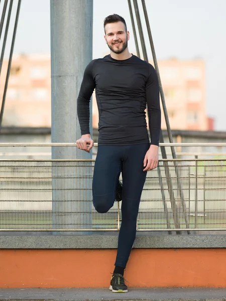 Joven corredor masculino tomando un descanso en puente urbano — Foto de Stock