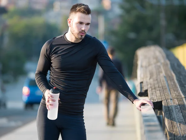 Jovem jogging homem com garrafa de plástico — Fotografia de Stock