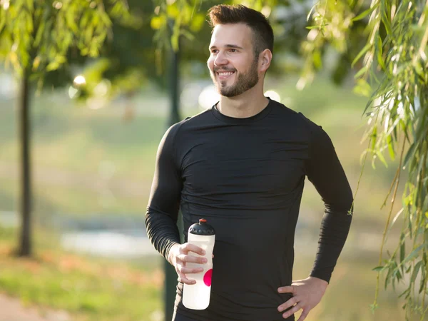 Jovem jogging homem com garrafa de plástico — Fotografia de Stock