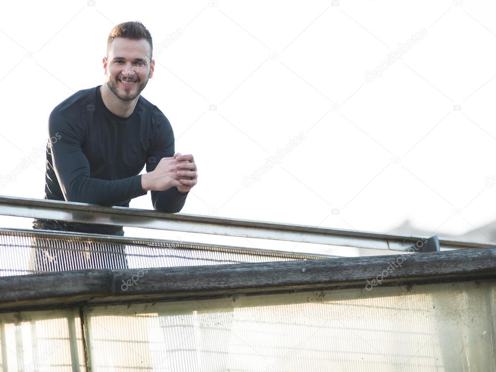 Portrait of Sport and fitness runner man resting on bridge after