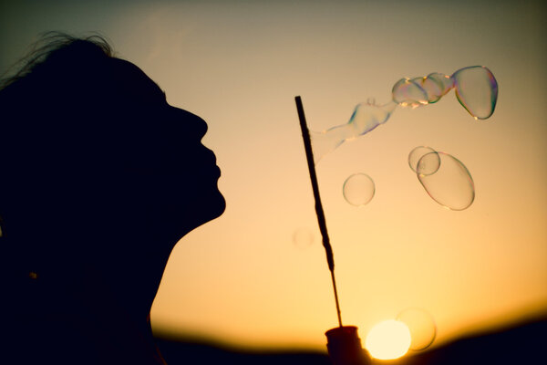Happy blowing bubbles in the park at sunset. instagram tone, ret