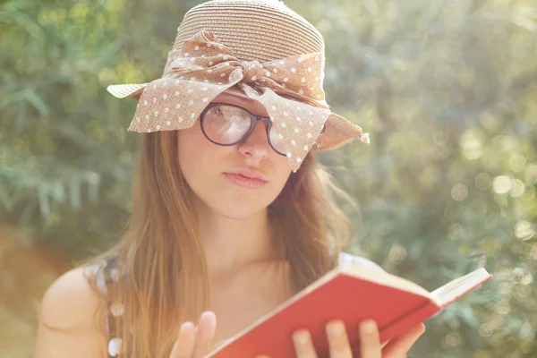 Menina bonita país lendo um livro na natureza, apreciando ensolarado — Fotografia de Stock