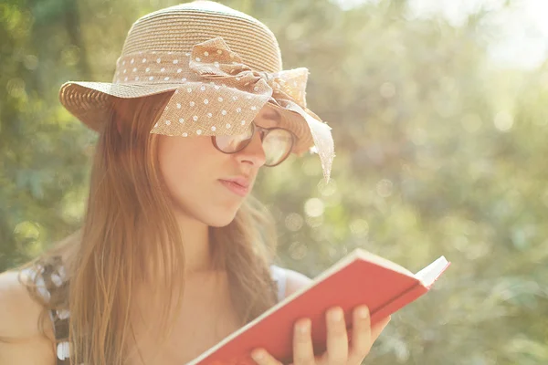 Menina bonita país lendo um livro na natureza, apreciando ensolarado — Fotografia de Stock