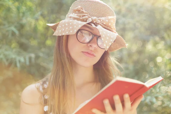 Menina bonita país lendo um livro na natureza, apreciando ensolarado — Fotografia de Stock