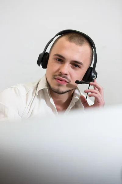 Sorrindo jovem casual com fone de ouvido usando o computador em um brilhante — Fotografia de Stock