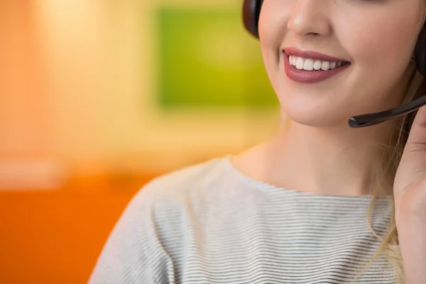 Close up de uma mulher sorrindo loira usando fone de ouvido em seu escritório — Fotografia de Stock