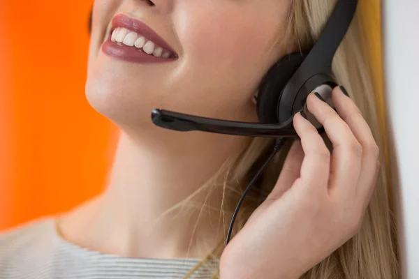Close up de uma mulher sorrindo loira usando fone de ouvido em seu escritório — Fotografia de Stock