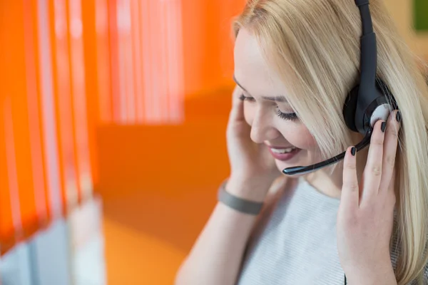 Usměvavá mladá podnikatelka nošení headsetem, odpovídání na volání — Stock fotografie